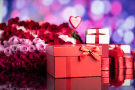 Valentines day theme. Gifts in boxes, red hearts and big bouquet of natural roses on blue bokeh background.の写真素材