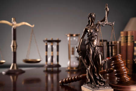 Judge office. Gavel, scale, Themis sculpture, hourglass and law books on the desk.の写真素材