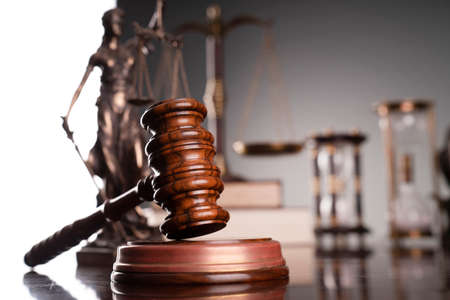 Judge office. Gavel, scale, Themis sculpture, hourglass and law books on the desk.