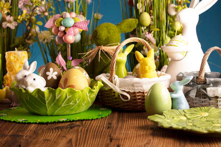 Easter time. Easter decorations on the rustic wooden table. Easter bunny, easter eggs in basket and...