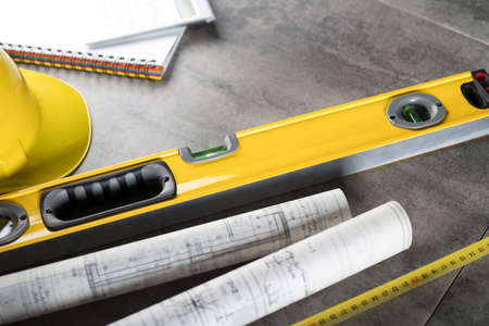 Contractor theme. Tool kit of the contractor: yellow hardhat, libella, hand saw. Plans and notebook...