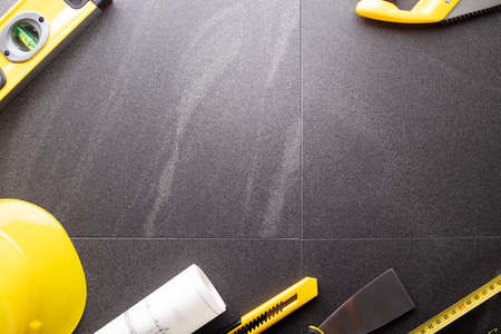 Business contraction theme. Tool kit of the contractor: yellow hardhat, libella, hand saw. Plans and...