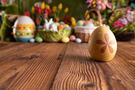Easter time. Easter decorations on the rustic wooden table. Easter bunny, easter eggs in basket and...
