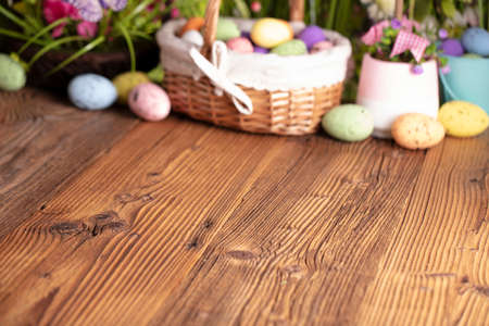 Easter time. Easter decorations on the rustic wooden table. Easter bunny, easter eggs in basket and cabbage leaf. Bouquets of spring flowers.の写真素材