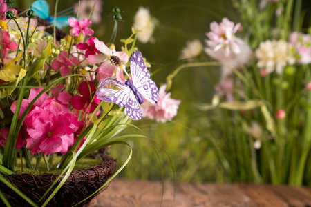 Easter time. Easter decorations on the rustic wooden table. Easter bunny, easter eggs in basket and cabbage leaf. Bouquets of spring flowers.の写真素材