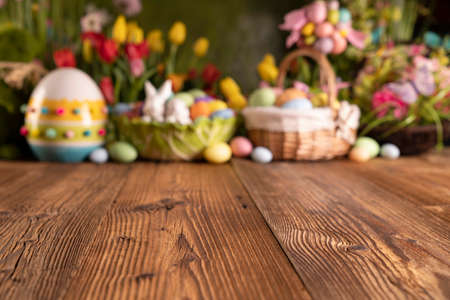Easter time. Easter decorations on the rustic wooden table. Easter bunny, easter eggs in basket and cabbage leaf. Bouquets of spring flowers.の写真素材
