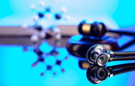 Medical law concept. Gavel, legal code and stethoscope on the glass table. Blue light.の写真素材