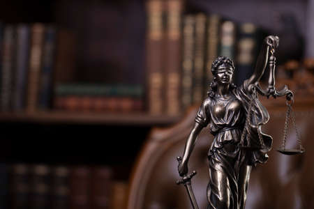 Judge office. Themis sculpture and gavel on the judge desk. Book shelf and judge chair in the background.の写真素材