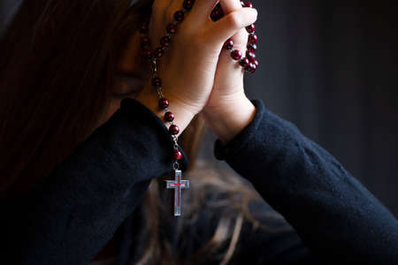 Christianity theme â prayer.  Christian woman with Bible praying with hands crossed keeping rosary.の写真素材