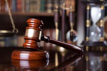 Judge office. Gavel and scale on the judge desk. Book shelf  in the background.の写真素材