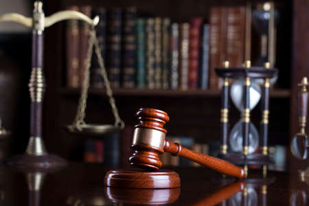Judge office. Gavel and scale on the judge desk. Book shelf  in the background.の写真素材