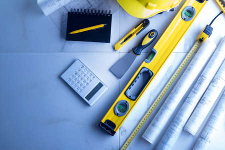 Contractor theme. Plans,  notebook and tool kit of the contractor: yellow hardhat, libella and yardstick.の写真素材