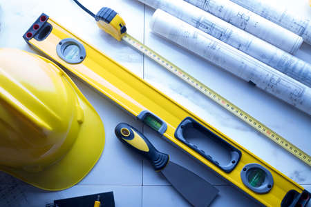 Contractor theme. Plans,  notebook and tool kit of the contractor: yellow hardhat, libella and yardstick.の写真素材