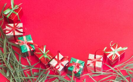 Christmas gift box with green leaves on red color background for Christmas and New year.の写真素材