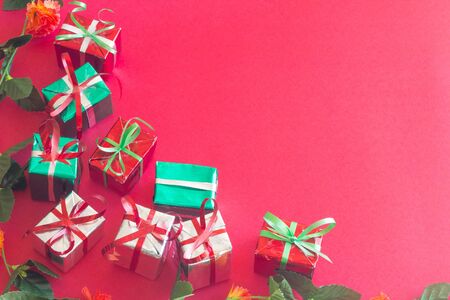 Christmas gift box with green leaves on red color background for Christmas and New year.の写真素材