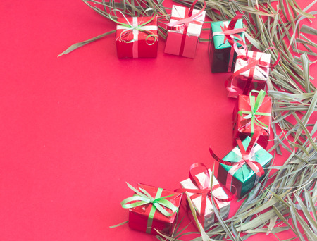 Christmas gift box with green leaves on red color background for Christmas and New year.の写真素材