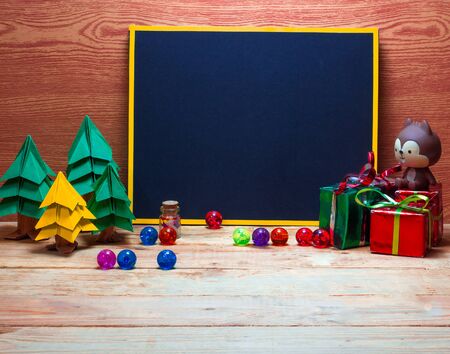 Blank blackboard for your text on wooden background with Christmas tree, gift box and Christmas ball decoration image for Christmas holiday concept.の写真素材