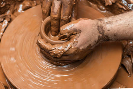 The sculptor in the workshop makes a jug out of earthenware closeup. Twisted potter's wheel.