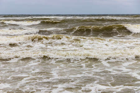 Dirty sea waves hitting the beach in stormy weather