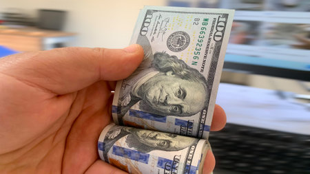 Pile of American one dollar cash. Next to it are several gold bitcoin digital cryptocurrency coins....