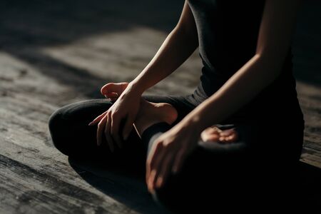 asian young woman sitting in Lotos pose. Businesswoman practicing meditation in yoga hall after finish working. Time for Yoga and relaxationの写真素材
