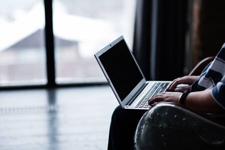 woman working on a laptop hands on the keyboard typing in a chair silver laptop black screenの写真素材