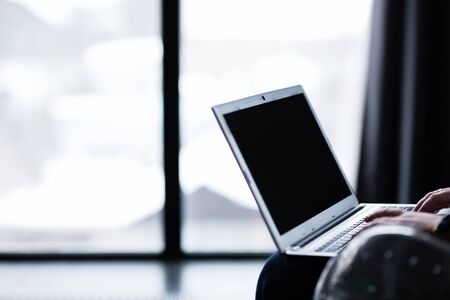 woman working on a laptop hands on the keyboard typing in a chair silver laptop black screenの写真素材