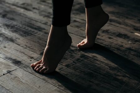 Female feet walking on warm heated floor close up view, barefoot girl legs going on hardwood living room wooden flooring at modern home house, domestic underfloor heating concept, close up rear viewの写真素材