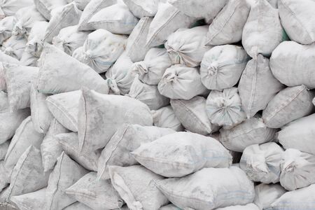 white bags with loose material lie on the street a little in the snow
