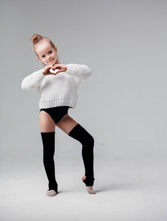 Gymnast girl posing against a white wall. Girl with blouse and knee socks.の写真素材