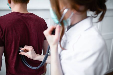 Therapist with a stethoscope listens to the patient's heartbeatの写真素材