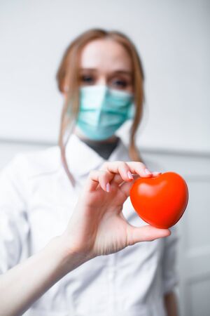 Close up photo Two red-hair cardiologist holding a red toy heart. An approximate photo of the hands of doctorsの写真素材