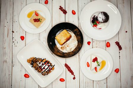Set of sweet desserts on a wooden background. The restaurant dish on the table is decorated with...