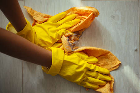 Cleaning the house during the quarantine. The girl washes the dirty and dusty floor with the yellow...
