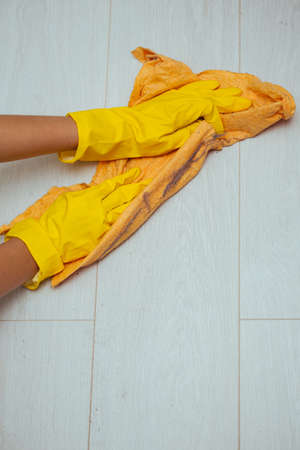 Cleaning the house during the quarantine. The girl washes the dirty and dusty floor with the yellow cloth protective gloves yellowのeditorial素材