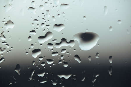 Macro pure rain drops on the glass against a cloud gray background
