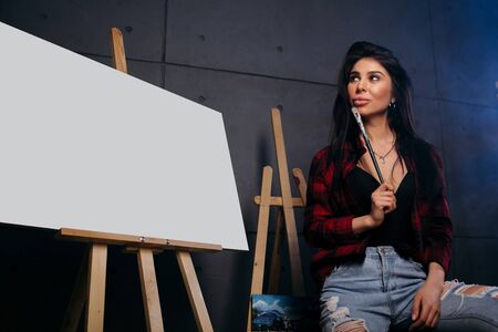 Blank Mock Up Canvas. The artist in a red plaid shirt with a brush in hands rejoices in the fact that I finished an abstract colorful paintingの写真素材