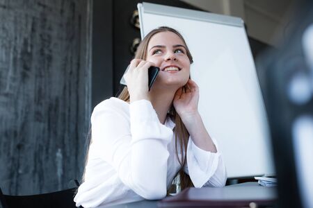 Corporate Communication. Businesswoman talking on a smartphone with a potential client, smiling and making an appointment.の写真素材
