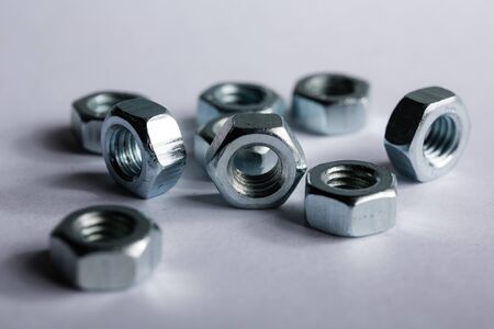 Metal nuts neatly laid out on a white background. Macro shooting. Construction and repair conceptの写真素材
