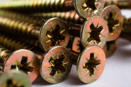 Macro shot of yellow zinc plated wood screws. Several nails lie on a white backgroundの写真素材
