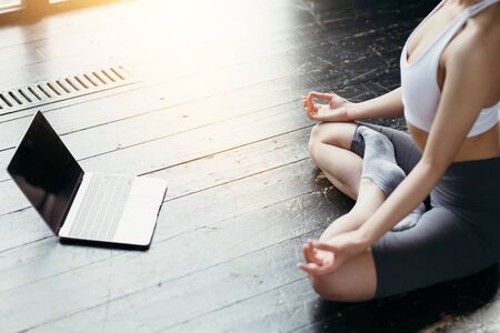 Close-up of laptop screen with a black screen to insert your image and a yoga trainer meditating in lotus position under the videoの写真素材