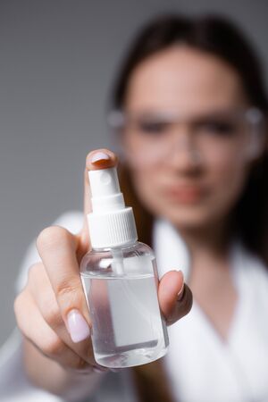 Close-up. An italian doctor in medical clothing and protection sends an antiseptic to the camera....