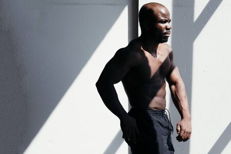 A black male model demonstrates his muscular body in the sunlight. Sport and healthy lifestyle conceptの写真素材