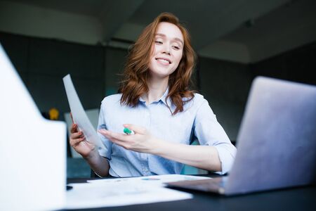A red-haired girl holds a presentation of a business plan to investors through video calling on a...