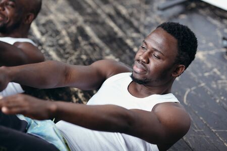 Close-up of a dark-skinned sportsman press-swinging in the studio with his trainer.