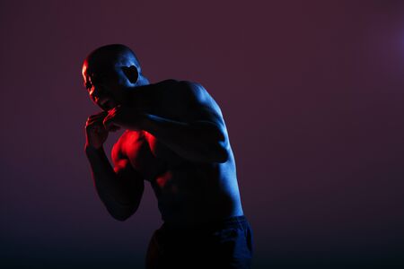 An African American in a red-blue neon color with a naked torso stood in a combat pose in the...