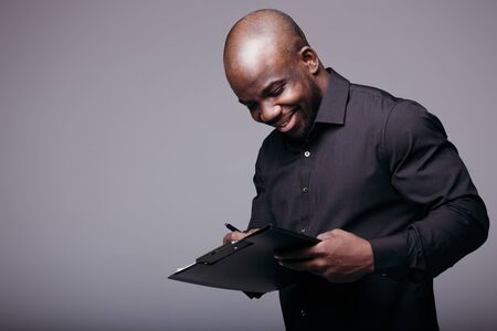 Bald black male office worker holds the document folder and pen. The signing of an important...