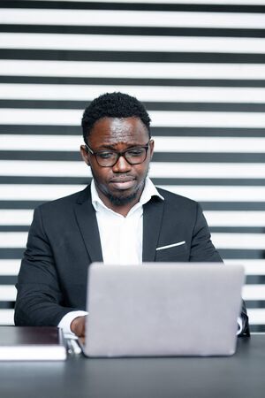 African office worker programmer is developing a new application on a laptop. The workflow of a...