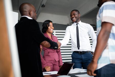 A black male businessman shakes hands with his new partner, an African American in a white shirt and smiles. Make a deal.の写真素材