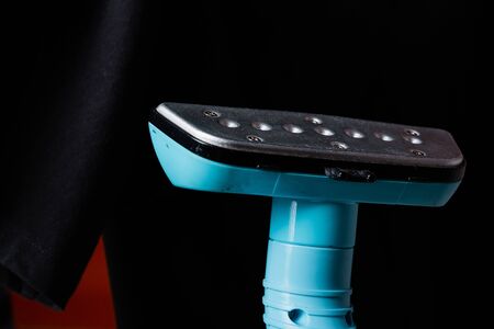 Close-up of professional steam against the dark ironed t-shirt. Equipment business chemical cleaningの写真素材
